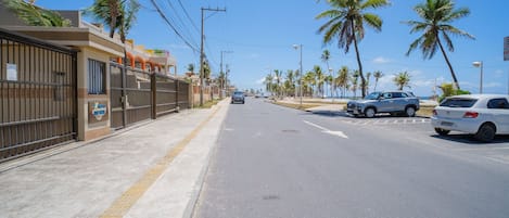 A street with parked cars, a sidewalk, and palm trees.