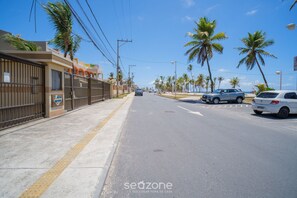A street with parked cars, a sidewalk, and palm trees.