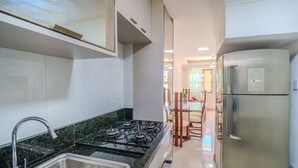 Una cucina moderna con piano cottura a gas, frigorifero in acciaio inossidabile e zona pranzo con tavolo e sedie.