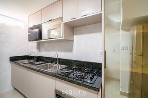 A kitchen with a gas stove, two sinks, and a microwave.