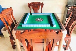 Una mesa de billar con superficie de fieltro verde, rodeada de sillas de madera con intrincados grabados.