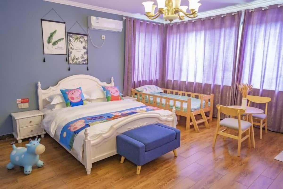 Un dormitorio con cama, cuna, mesita de noche, silla y una pequeña mesa.