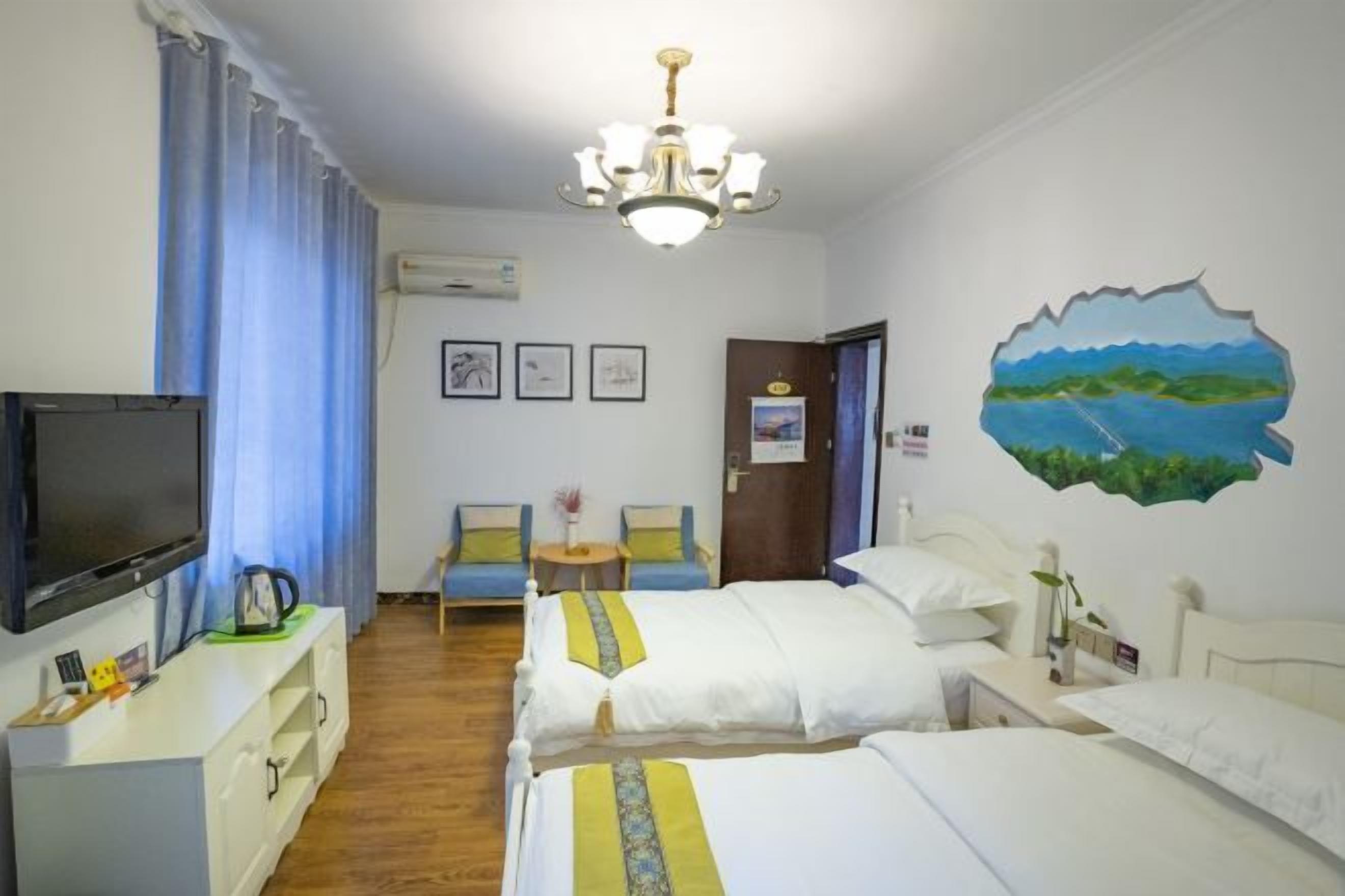 A hotel room with two beds, a TV, a desk, a chair, and a painting on the wall.