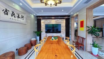 A conference room with a long wooden table, chairs, a television screen, and a chandelier.