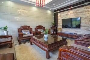 Una sala de estar moderna con un televisor de pantalla plana grande, muebles de madera y una pared de acento de piedra.