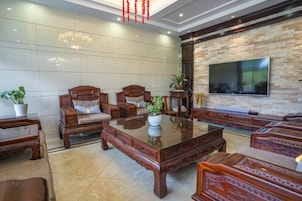 A modern living room with a large flat-screen TV, wooden furniture, and a stone accent wall.