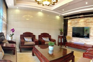 Una sala de estar moderna con un televisor de pantalla plana, muebles de madera, una mesa de centro de vidrio y una pared de acento de piedra.