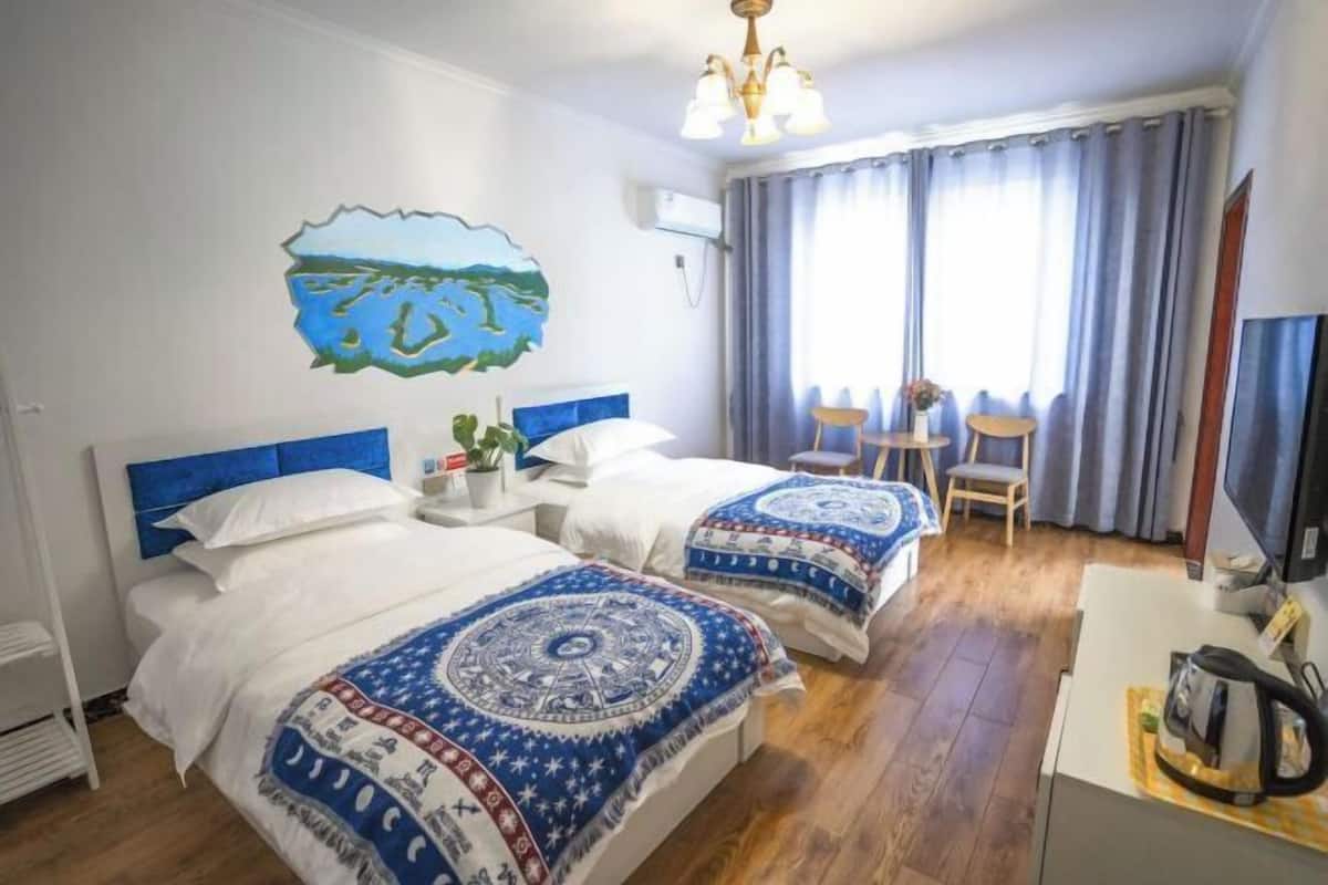 Una habitación de hotel con dos camas, un escritorio, una silla y un televisor.