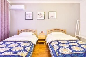 Een kamer met twee bedden, een klein tafeltje en drie afbeeldingen in lijsten aan de muur.