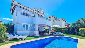 Uma casa de dois andares com piscina, área de estar externa e um jardim bem cuidado.