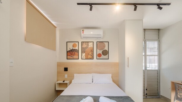 Habitación de hotel con cama, escritorio y ventana con persianas.