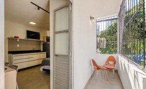 Ein kleiner Balkon mit Metallgeländer, einem Stuhl und einem Tisch.