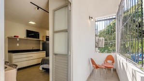 Un pequeño balcón con barandilla de metal, una silla y una mesa.