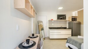 Una camera d'albergo funzionale con angolo cottura, un letto, un tavolo da pranzo e uno specchio.
