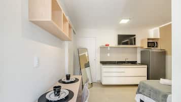 Een compacte hotelkamer met kitchenette, een bed, een eettafel en een spiegel.