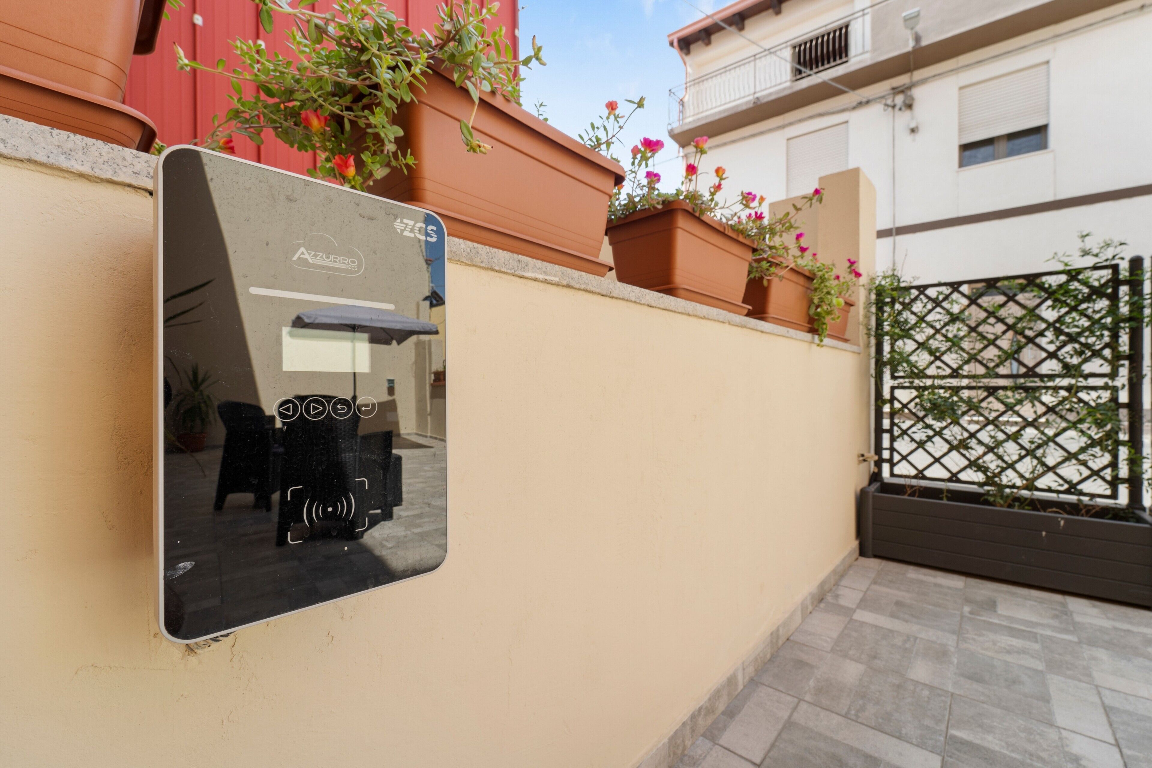 Un miroir mural qui reflète une pièce, une plante en pot et un portail.