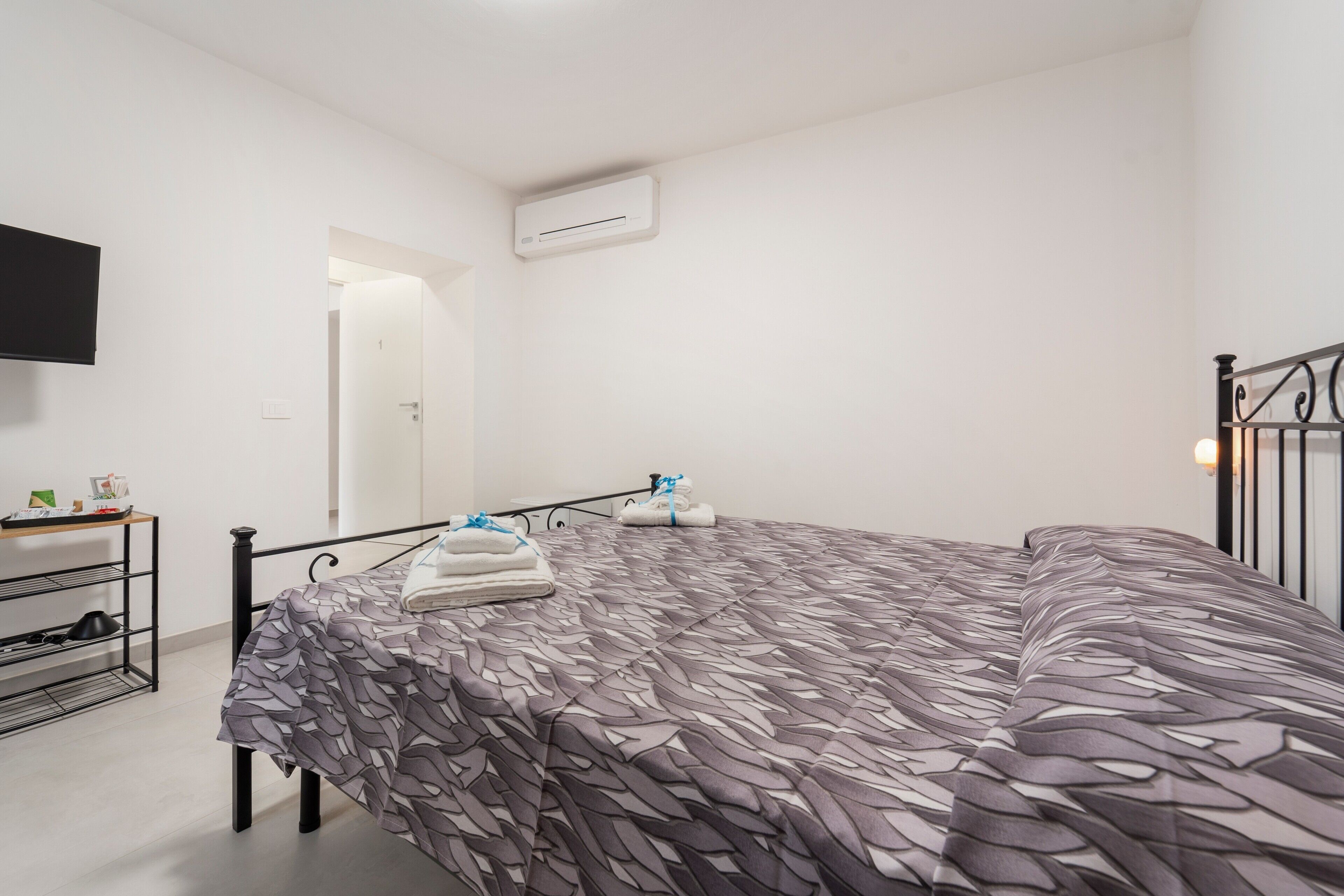 Ein Schlafzimmer mit Bett, Fernseher, Ablagefläche und Klimaanlage.