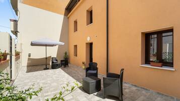 A courtyard with outdoor furniture, a white umbrella, and potted plants.