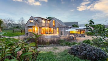 Una casa moderna con una amplia terraza, un espacio de estar al aire libre techado y un jardín bien cuidado.