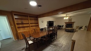 A dining area with a wooden table and chairs, a television, and a fireplace. - Parham Bridges #1 5 Bedroom 2 Bath (Jackson)