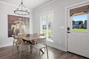 Un comedor con una mesa y sillas de madera, una araña y una ventana con persianas.