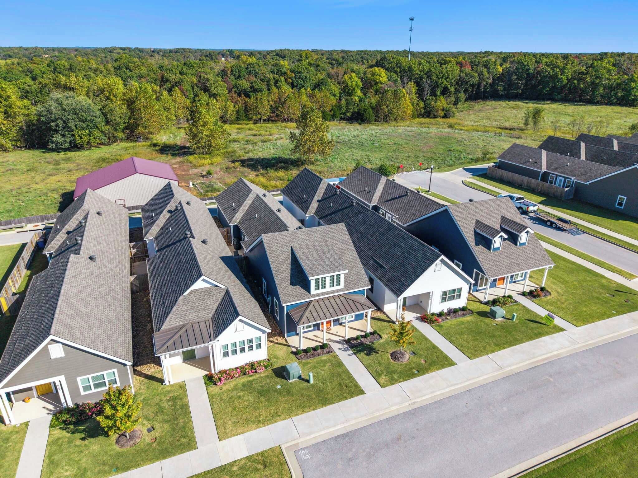 Un quartier résidentiel composé de plusieurs maisons, chacune ayant un toit en pente et un jardin devant.
