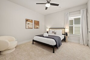 A bedroom with a bed, bedside tables, a ceiling fan, and a window with curtains.