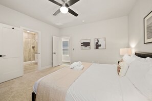 Un dormitorio con cama, ventilador de techo, mesita de noche y lámpara de pared.