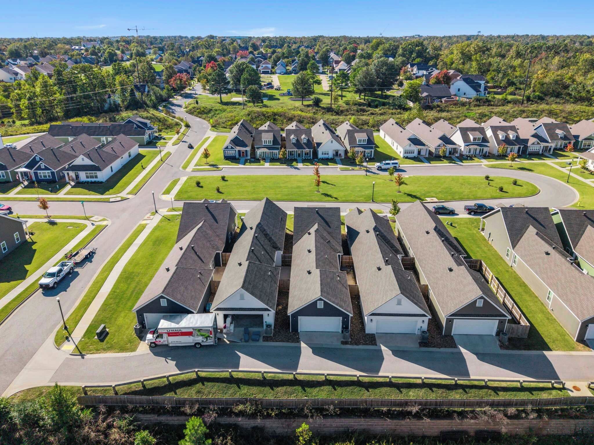 A suburban neighborhood with detached houses, a central road, and a L.L. Bean truck.