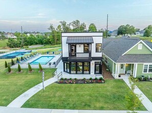 A two-story house with a balcony, a swimming pool, and a well-maintained lawn.