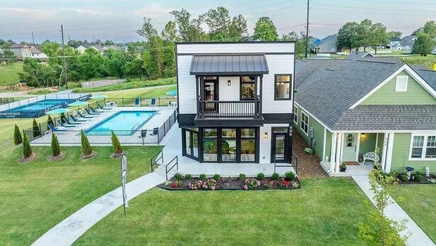A two-story house with a balcony, a swimming pool, and a well-maintained lawn.