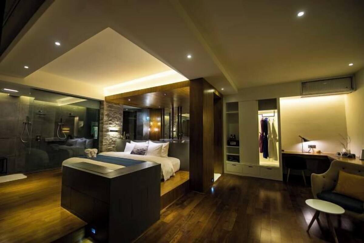 A modern hotel room with a large bed, a separate bathroom, a small seating area, and a desk.