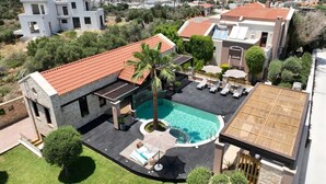 A modern house with a swimming pool, outdoor seating, and a view of the surrounding neighborhood.