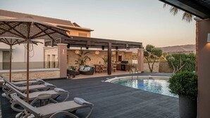 A poolside area with lounge chairs, a bar, and a pool.