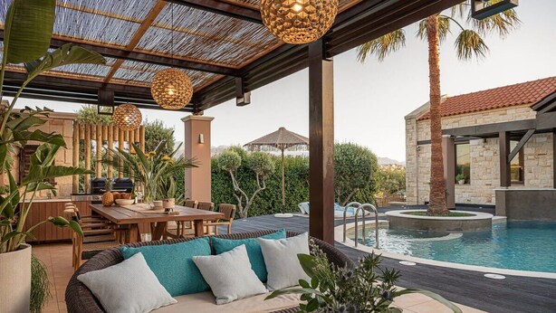 A covered outdoor area with a pool, seating, and a grill.