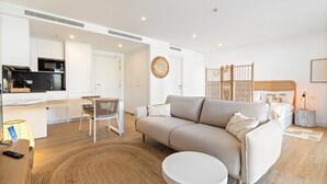 Een moderne, goed verlichte woonkamer met een bank, rond vloerkleed en een eettafel met stoelen.