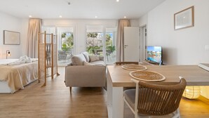 Een moderne hotelkamer met een bed, een bank, een eettafel en een televisie.