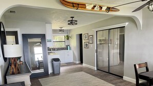 A modern kitchen with white cabinets, a black trash bin, and a large window.