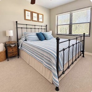 A bedroom with a bed, bedside table, lamp, framed pictures, and a window with blinds. - Peaceful Riverfront Retreat on the St. Johns River, dock access (Palatka)