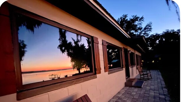 A building with large windows overlooking a body of water at sunset.