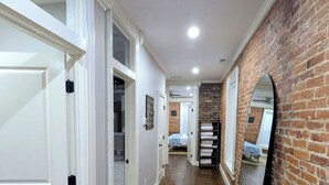 Un pasillo con puertas blancas, pared de ladrillo y suelo de madera.