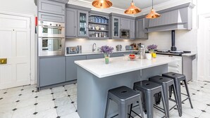 Una cocina moderna con armarios grises, una isla blanca y lámparas colgantes de cobre.