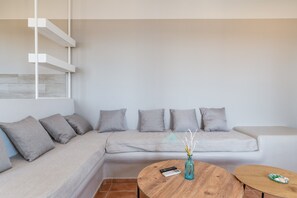 Una sala moderna con un sofá modular, una mesa de centro de madera y un florero con ramas.