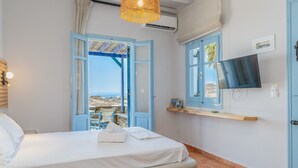 A bedroom with a bed, a television, a wicker light fixture, and a view of the sea. - Apartment 'Unit 2' with Sea View, Wi-Fi and Air Conditioning (Tinos)