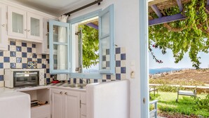 Eine Küche mit weißen Schränken, einer Mikrowelle und einem Fenster mit blauen Fensterläden.