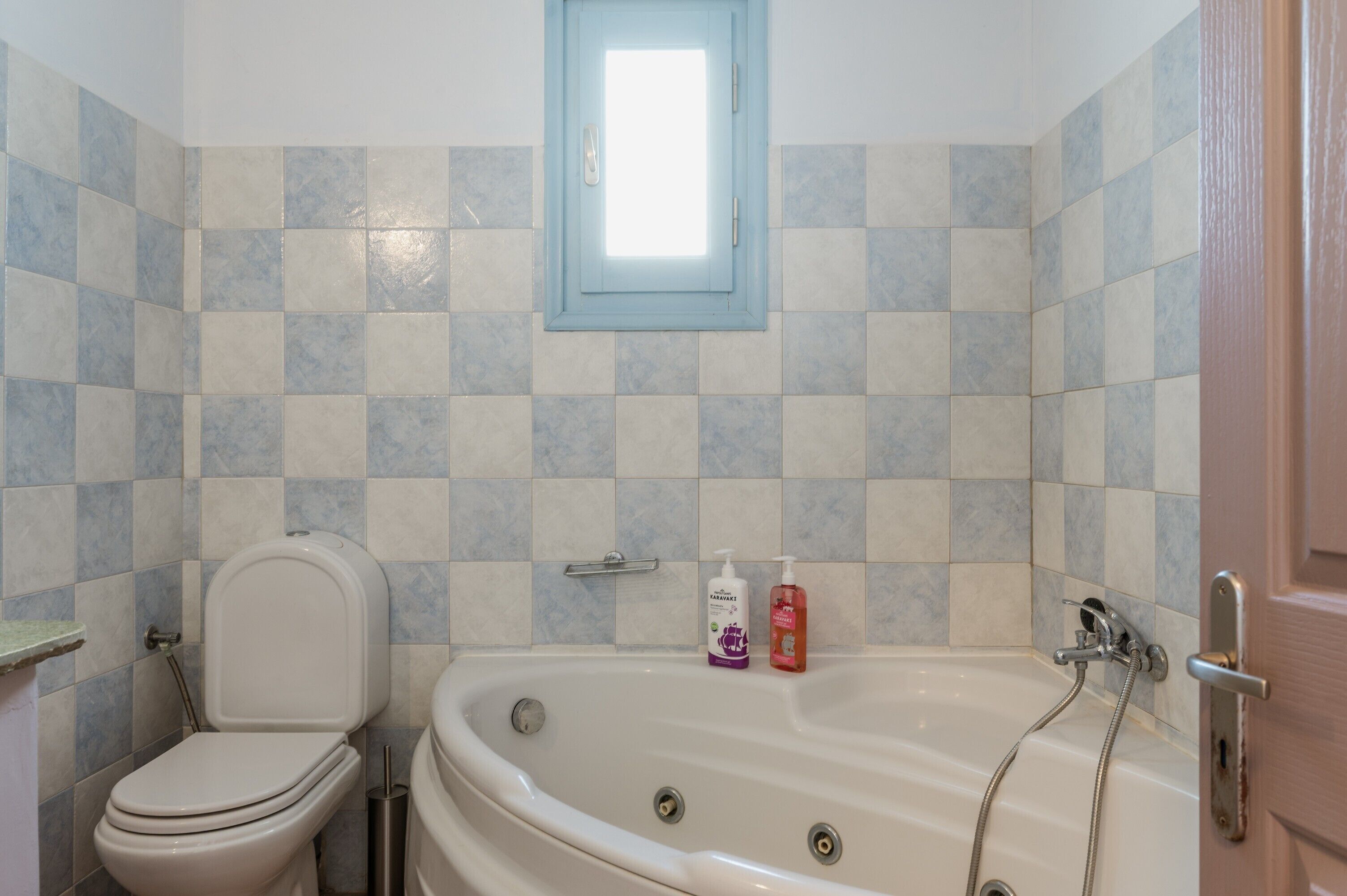 A bathroom with a toilet, a bathtub, and two bottles of shampoo.
