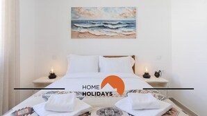 Habitación de hotel con cama, dos mesitas de noche con lámparas, un cuadro de olas y toallas sobre la cama.