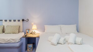 A hotel room with a bed, bedside table, lamp, and a picture frame. - Apartment '5' with Sea View, Wi-Fi and Air Conditioning (Tinos)