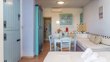 A room with a bed, a dining table with chairs, a kitchenette, and a bathroom with a shower.