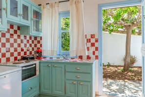 A kitchen with a checkered backsplash, a Bosch oven, and a window with curtains.